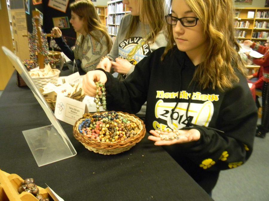 Senior Ashley Sabin looks at bracelets for a birthday present. “The money goes to a great cause,” Sabin said. “The jewelry is unique and you would never know by looking at them that they are made from paper.